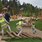Dzieci w odblaskowych kamizelkach biegające i bawiące się na drewnianym placu zabaw.