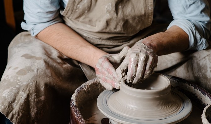 Zdjęcie przedstawia człowieka lepiącego gliniane naczynie.