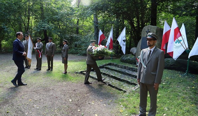 Dyrektor generalny składa wieniec pod pomnikiem, w tle widać poczet sztandarowy leśników. Sławomir Fiedukowicz