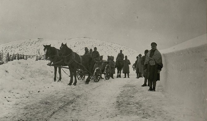 Na czarno-białym zdjęciu widać żołnierzy idących i jadących na wozie przez zaśnieżoną drogę/ Zbiory R. Eryka
