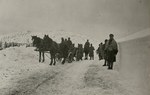 Na czarno-białym zdjęciu widać żołnierzy idących i jadących na wozie przez zaśnieżoną drogę/ Zbiory R. Eryka