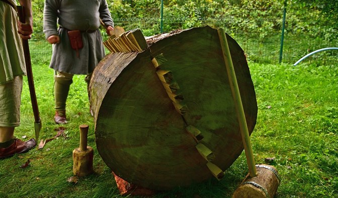 Fotografia przedstawia drewno z wbitymi w niego klinami.