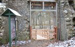 Na fotografii jest widoczna zbudowana z kamienia brama, w dalszym planie widać drewnianą kładkę/  Fot. M. Majchrzyk