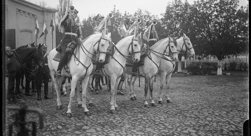 Na czarno-białej fotografii widać mężczyzn w mundurach, którzy siedzącą na koniach