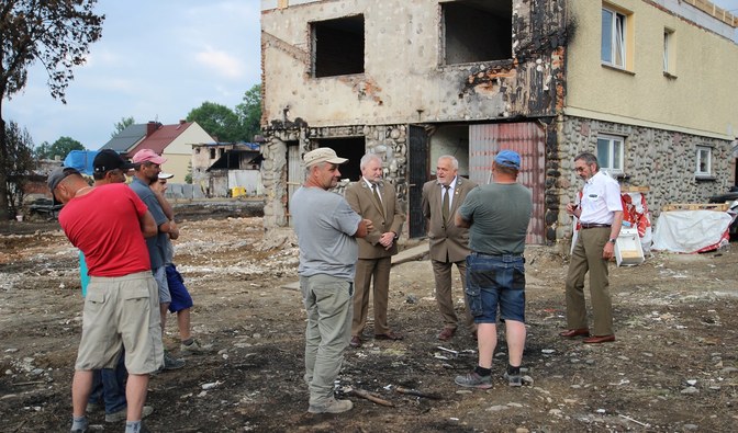 Na zdjęciu jest widoczna grupa mężczyzn stojących przed zniszczonym budynkiem/ Fot. Daniel Kusper, Nadleśnictwo Nowy Targ