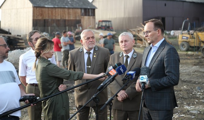 Na zdjęciu jest widoczna grupa mężczyzn oraz dziennikarzy stojących na podwórku przed zniszczonym budynkiem/ Fot. Daniel Kusper, Nadleśnictwo Nowy Targ