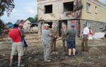 Na zdjęciu jest widoczna grupa mężczyzn stojących przed zniszczonym budynkiem/ Fot. Daniel Kusper, Nadleśnictwo Nowy Targ