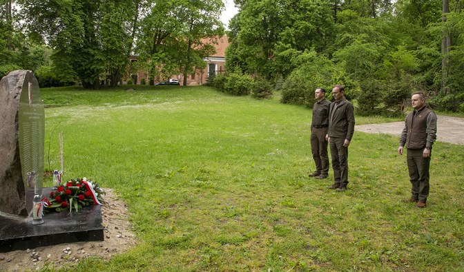 Na zdjęciu są widoczne dwie osoby, mężczyźni, stojący na polanie przed pamiątkowym kamieniem/ Fot. Bartosz Klamra