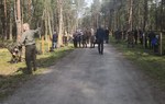 Na zdjęciu są widoczni ludzi idący leśną drogą