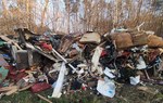 Na zdjęciu widać bardzo dużą ilość śmieci - zniszczone materace oraz połamane meble - wyrzucone w lesie