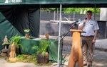 Na zdjęciu widać przemawiającego mężczyznę, który trzyma mikrofon, obok niego ustawiono stół przykryty zieloną tkaniną/ Arch. nadleśnictw Mrągowo i Srokowo
