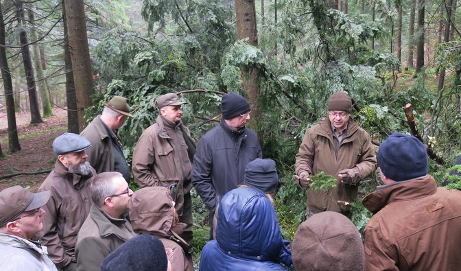 Grupa uczestników konferencji podczas jej plenerowej części stoi w lesie.